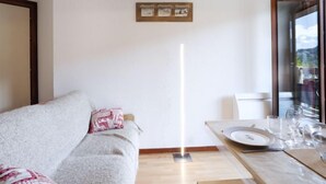 Un soggiorno moderno con un divano, un tavolo da pranzo per due persone e una lampada da terra alta.