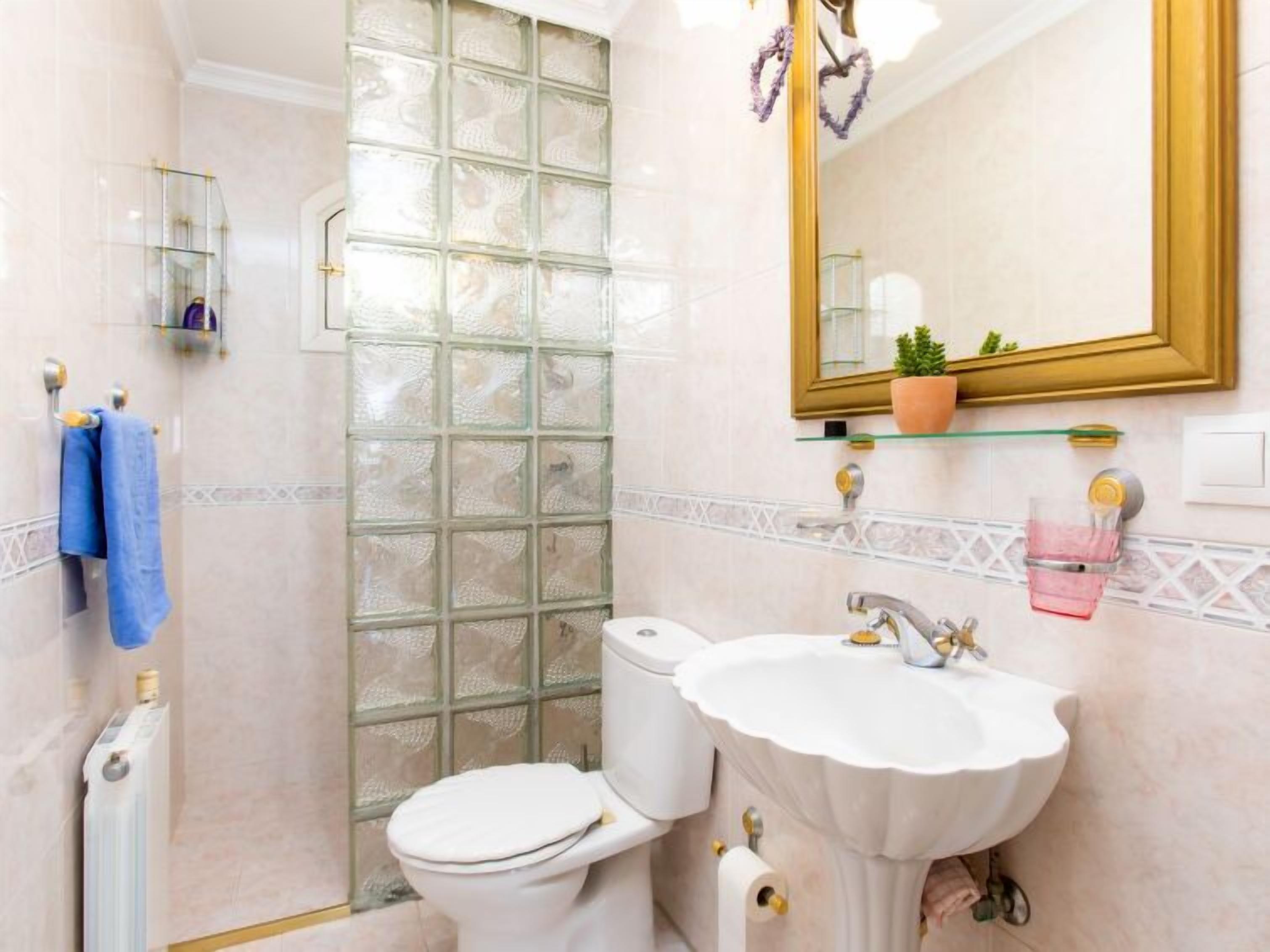 Een badkamer met toilet, wastafel en een douchecabine met glazen wanden.