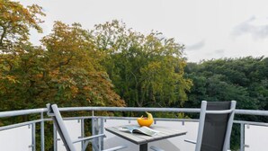 A balcony with a table and two chairs, a yellow bowl with fruit, and a book. - App.18 Zinnowitzer Hof by Interhome (Zinnowitz)