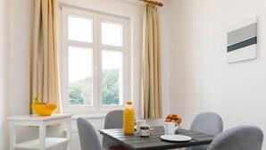 A dining area with a table, chairs, a white shelf, and a window with curtains. - App.18 Zinnowitzer Hof by Interhome (Zinnowitz)