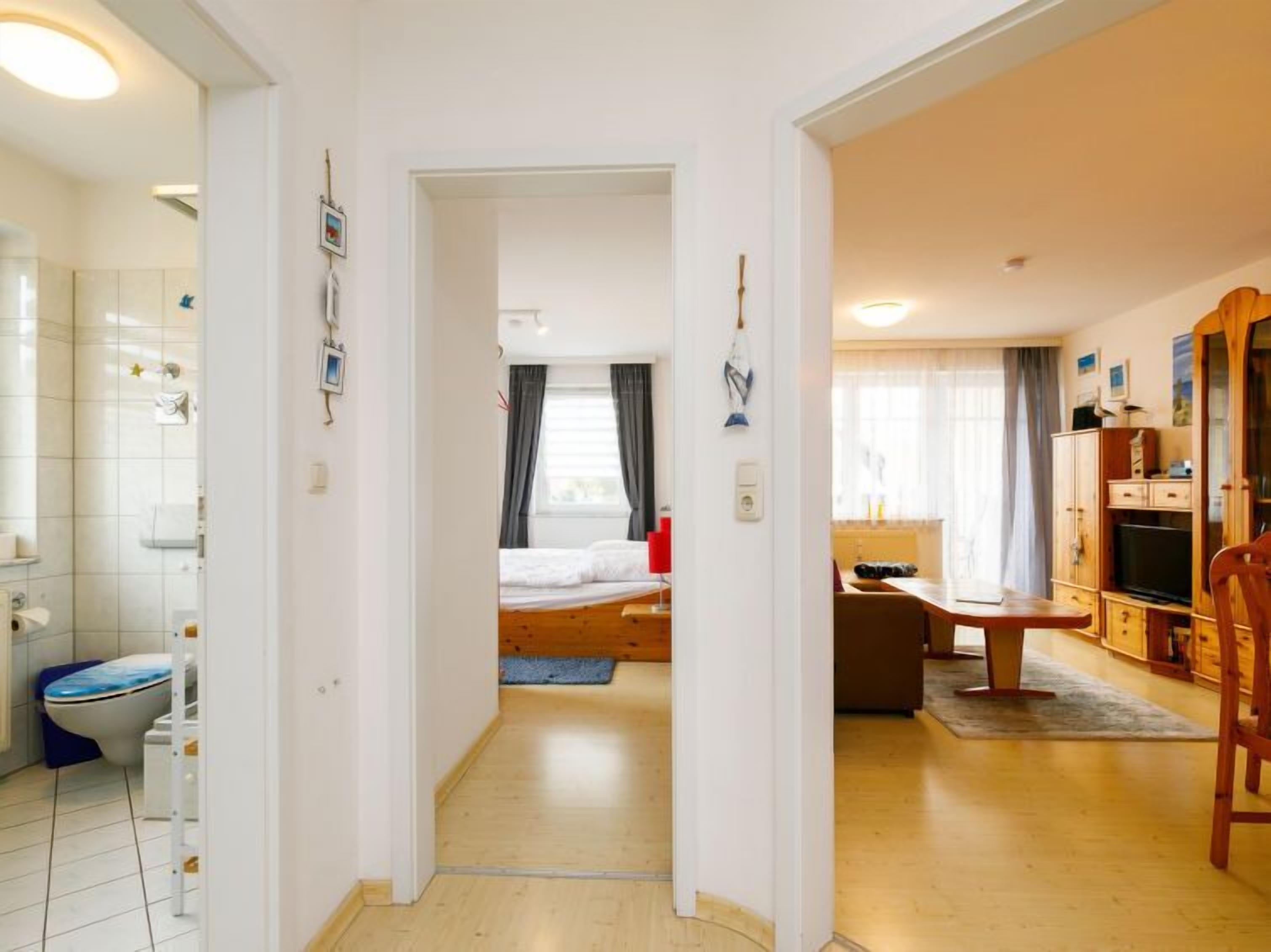 A hotel room with a bathroom, a bed, a desk, and a TV.