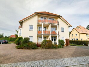 A multi-story residential building with a balcony on the second floor, a driveway, and surrounding greenery. - Schwarz by Interhome (Koserow)