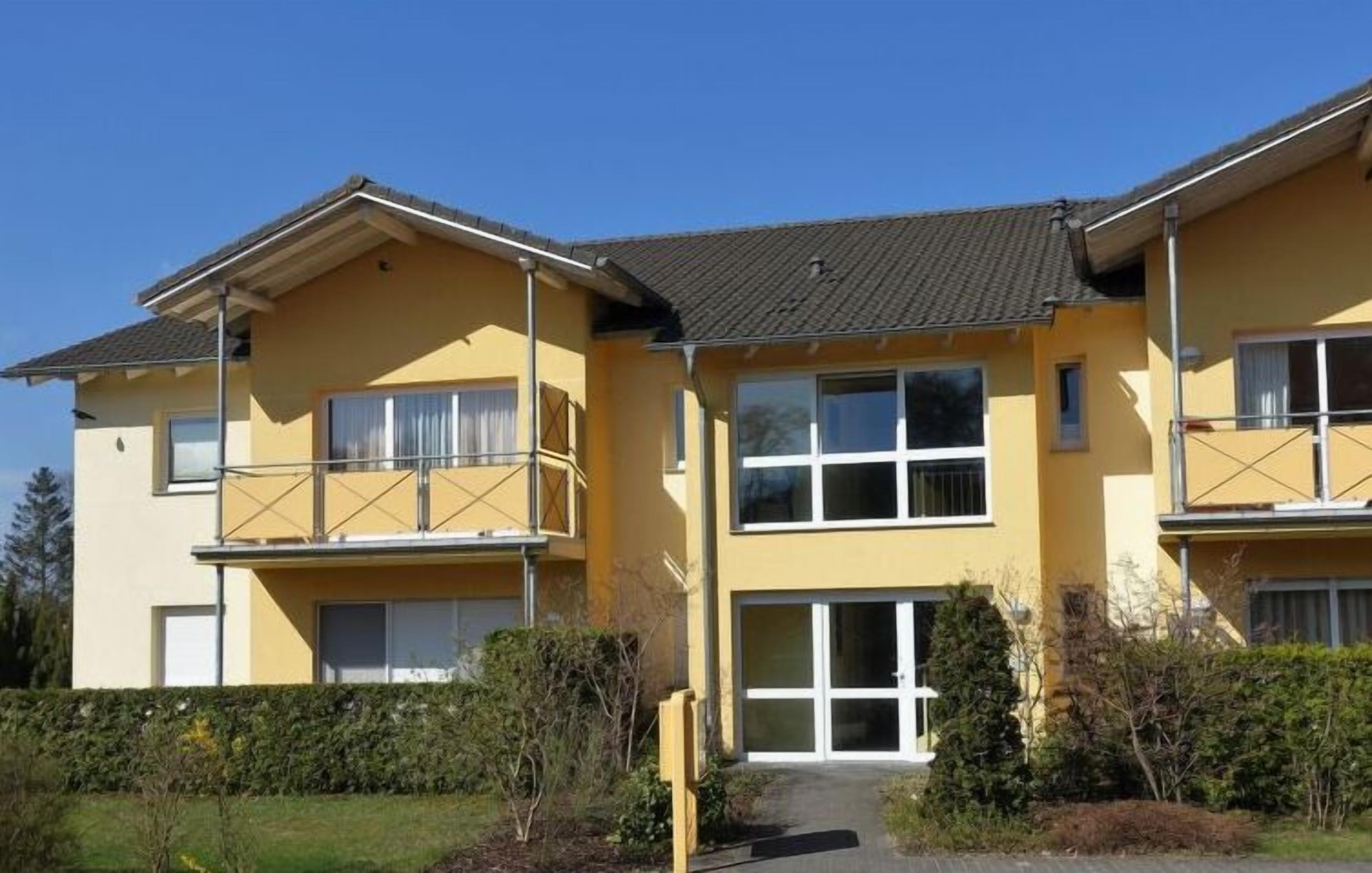 Un edificio a due piani con facciata gialla, ampie finestre e un ingresso coperto.