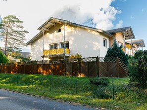 A two-story house with a balcony, a fenced yard, and a clear sky. - Apartment Neptun by Interhome (Koserow)
