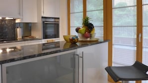 Eine moderne Küche mit weißen Schränken, einer schwarzen Arbeitsplatte, einem Edelstahlbackofen und einer Obstschale auf der Kücheninsel.