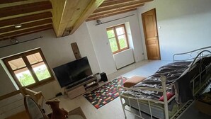 Una habitación con una cama litera, televisión, una mesa de madera y ventana.