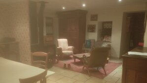 Una sala de estar con una mesa de comedor, sillas, un sofá y un televisor.