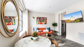 A modern living room with a marble table, orange sofa, and artwork on the walls.
