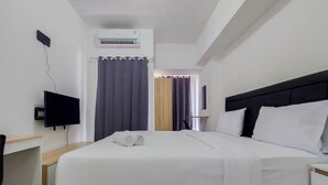 Hotellihuone, jossa on sänky, televisio, työpöytä ja ilmastointilaite.