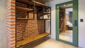 A room with a brick wall, wooden shelves, a green door, and a bed with white bedding. - H5063 (Buenos Aires)