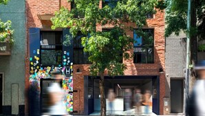 A multi-story building with a brick facade, large windows, and a tree in front. - H5063 (Buenos Aires)