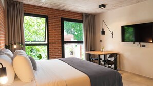 A modern hotel room with a large bed, a dining table, and a TV mounted on the wall. - H5063 (Buenos Aires)