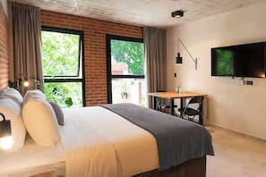 Ein modernes Hotelzimmer mit einem großen Bett, einem Esstisch und einem an der Wand befestigten Fernseher.