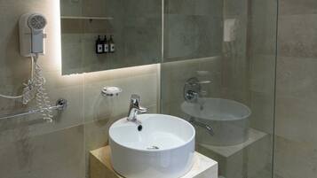 A modern bathroom with a glass-enclosed shower, a large mirror, and a white sink.