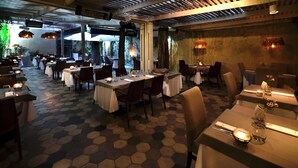 A restaurant with hexagonal patterned flooring, multiple tables set with white tablecloths, and hanging pendant lights. - H5063 (Buenos Aires)
