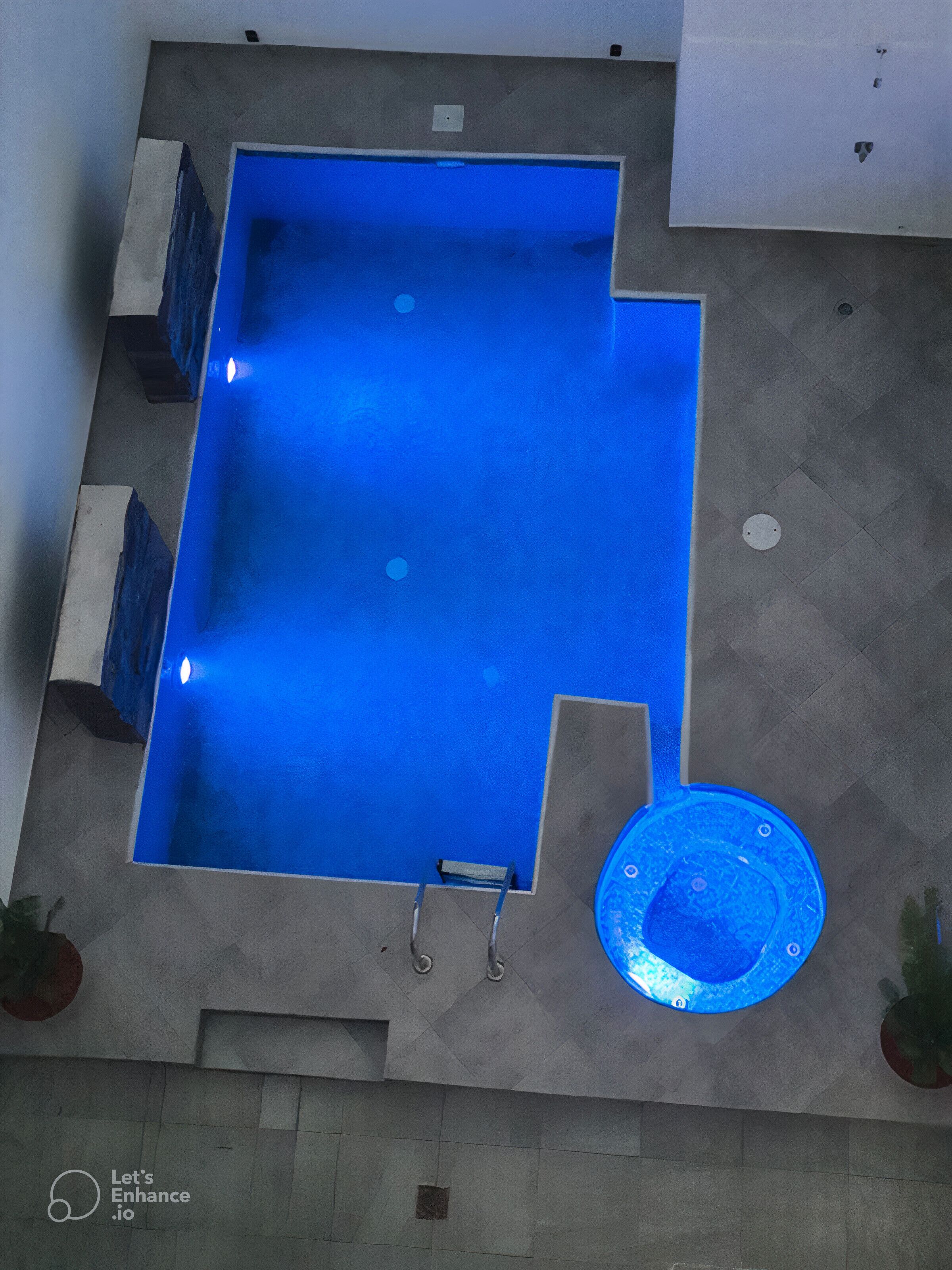 Vista aérea de una piscina rectangular con un jacuzzi circular adyacente.