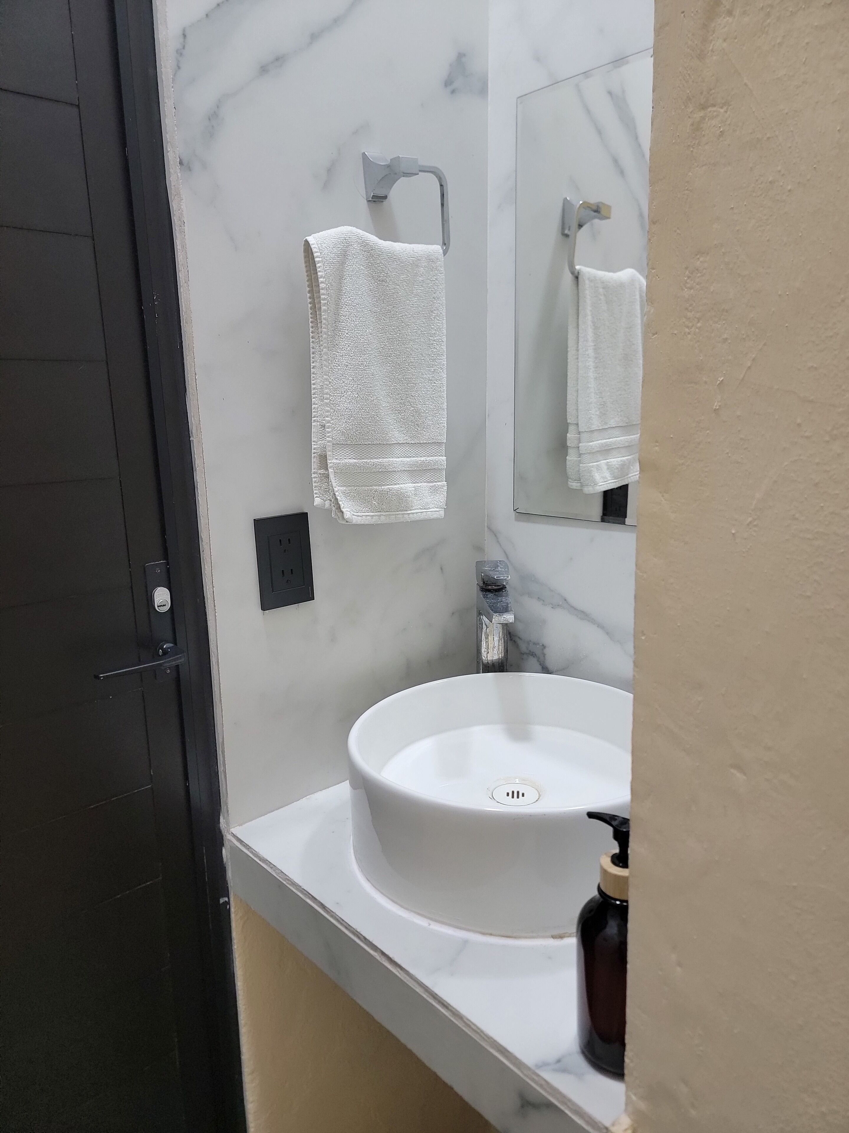 Ein Badezimmer mit einem weißen Waschbecken, einem Spiegel und einem Handtuch an der Wand.