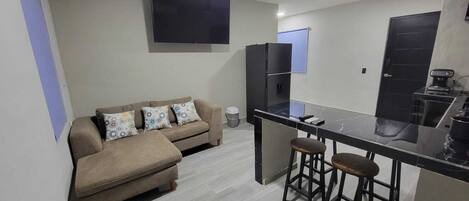 A compact living space with a sofa, a small kitchen area, and a ceiling fan.