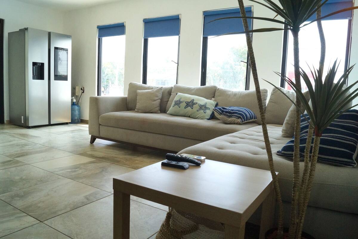 A living room with a sofa, a coffee table, and a refrigerator.