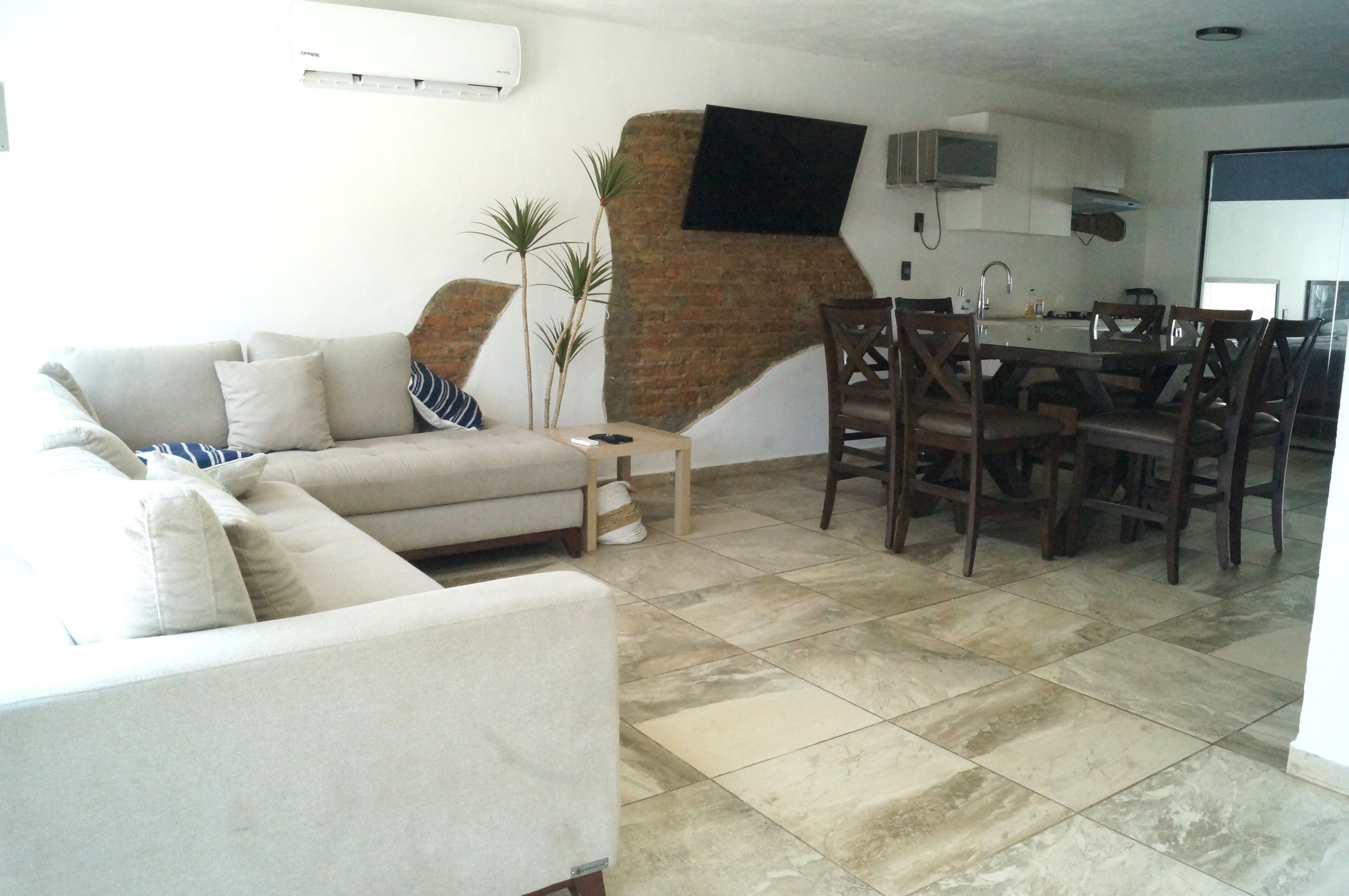 A living room with a sofa, a coffee table, and a dining area with chairs and a table.