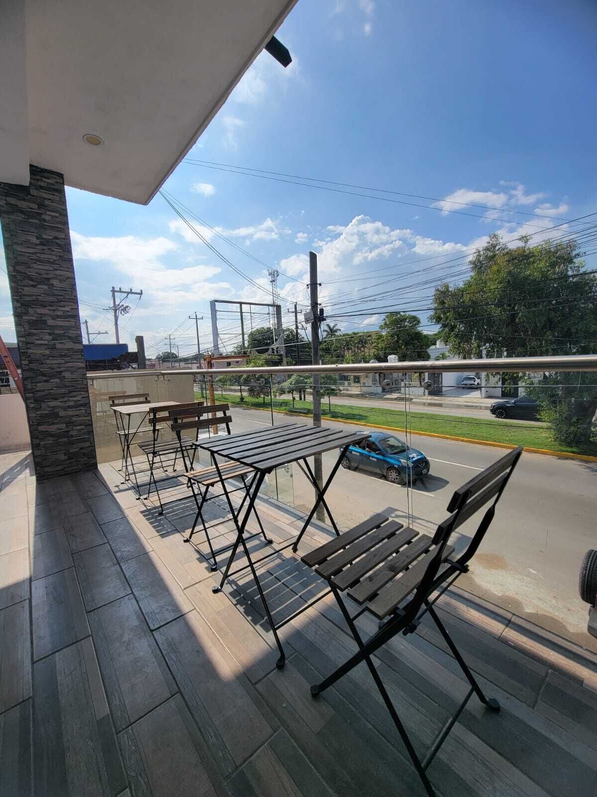 Un balcon avec du mobilier d’extérieur, une vue sur la rue et un ciel dégagé.