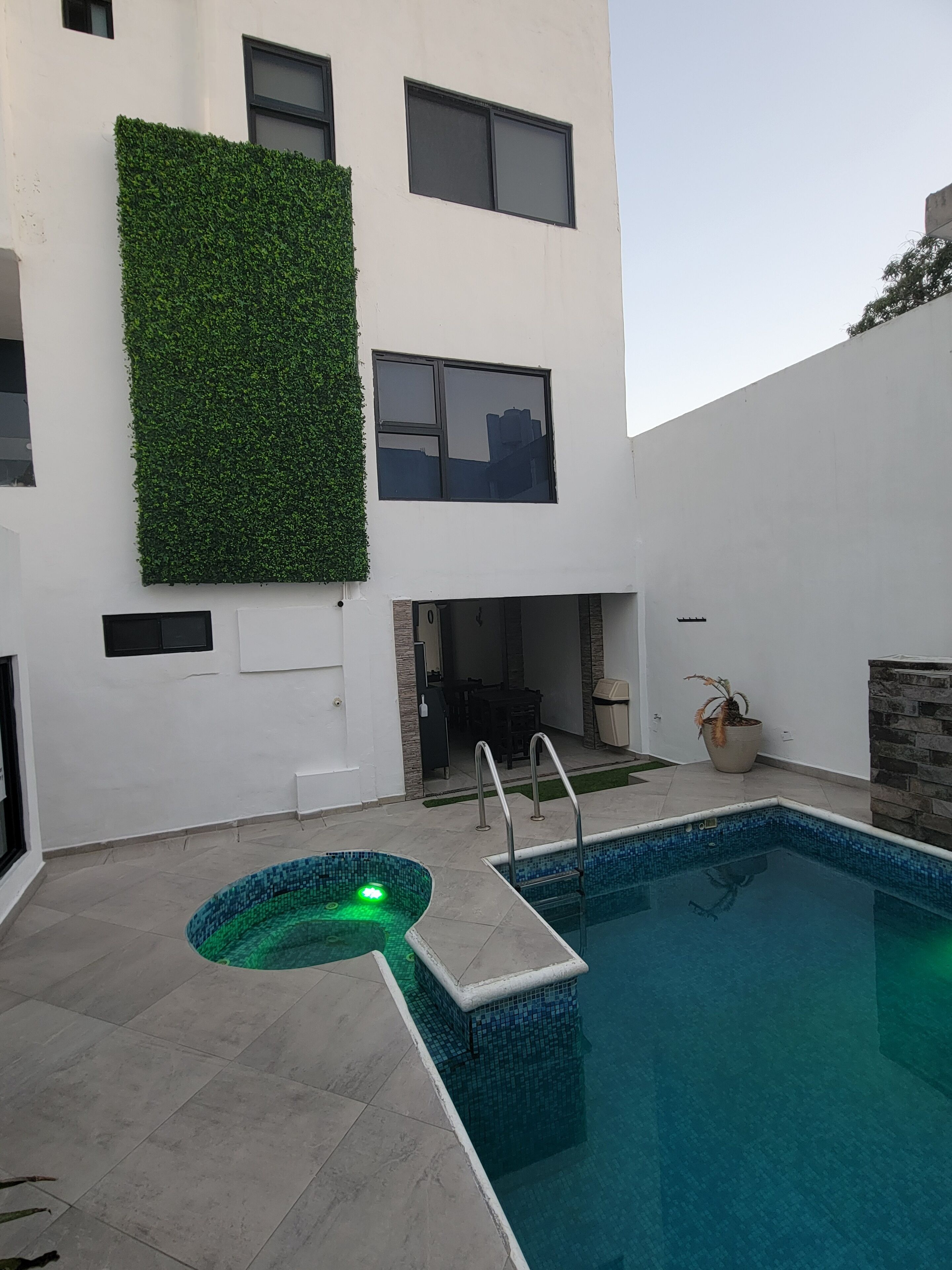 Un edificio moderno con piscina, un muro verde y una zona de patio.