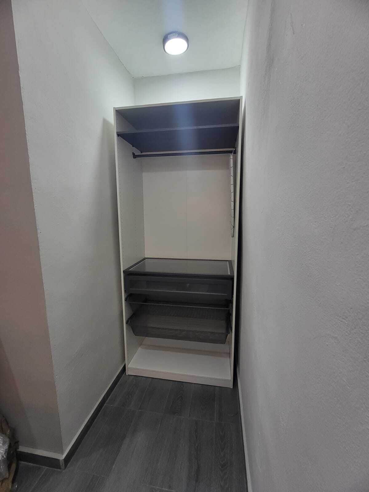 Un pasillo estrecho con un armario empotrado, una puerta corrediza y un escalón pequeño.