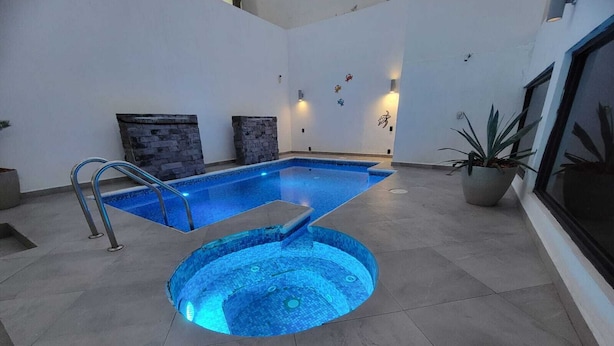An indoor swimming pool with a hot tub, stone walls, and potted plants. - FIESTA MIRAMAR (Ciudad Madero)