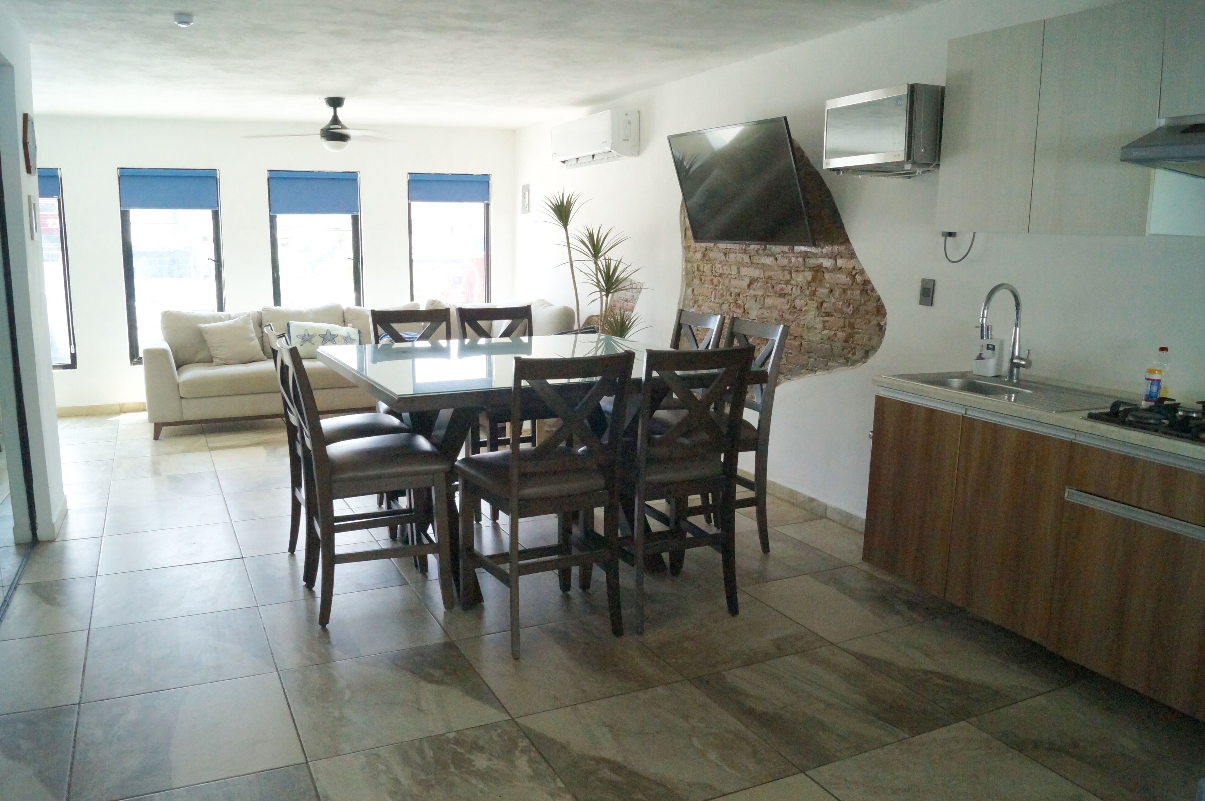 Una cocina moderna con comedor, que incluye una mesa grande, sillas, estufa integrada y un televisor montado en la pared.