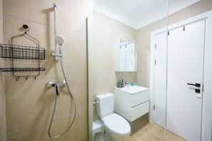 A bathroom with a shower, toilet, sink, and a mirror.