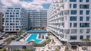 A modern hotel with multiple floors, a central swimming pool, and a well-maintained outdoor area.
