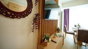 Ein modernes Wohnzimmer mit großem Fernseher, Holzvertäfelung und einem Essbereich mit Tisch und Stühlen.