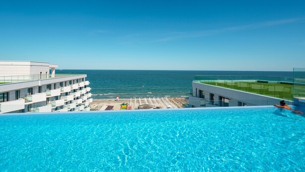 Ein Hotel mit Pool, das Meerblick bietet, ein Strand und ein klarer Himmel.
