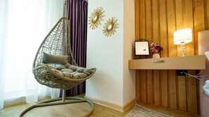 Ein Zimmer mit Hängesessel, Holzwand und Nachttisch mit Lampe.