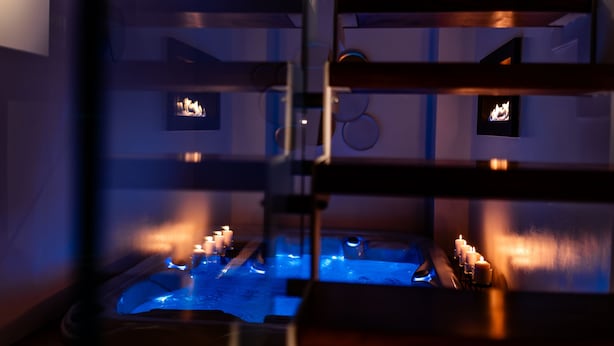 Et spa-område med jacuzzi, stearinlys og en trækonstruktion.