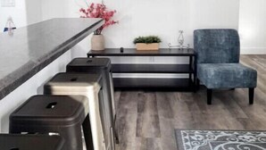 A modern kitchen with a bar area, a flat-screen TV mounted on the wall, and a blue chair. - Two Bedroom Farmhouse Cottage No. 3
 (Orderville)