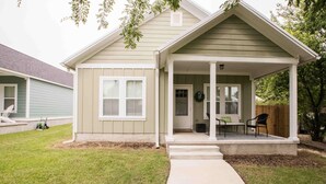 A single-story house with a covered porch, a front door, and a small seating area with two chairs. - Chic Thomasville Home: Walk to Downtown! (Thomasville)