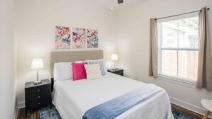 A bedroom with a bed, two bedside tables, a ceiling fan, and a window with curtains. - Chic Thomasville Home: Walk to Downtown! (Thomasville)