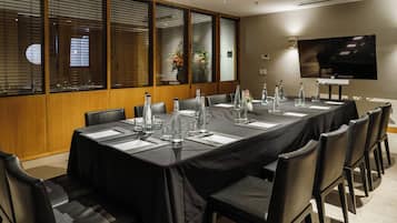 Un salón de conferencias con una larga mesa, mantel negro y sillas a juego.