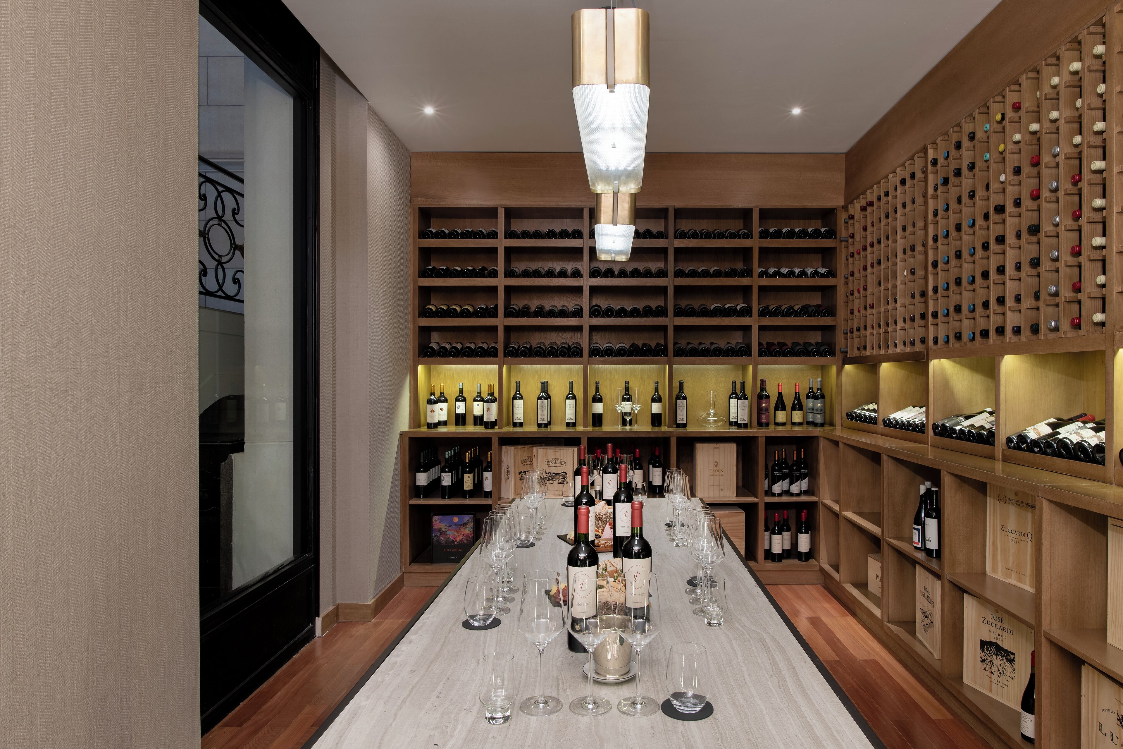 A wine cellar with rows of wine bottles and a long table with wine glasses.