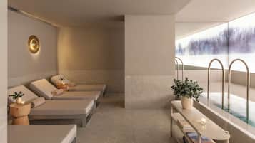 Un espacio de spa con tres camillas de masaje, un banco y una mesita con una planta y velas.