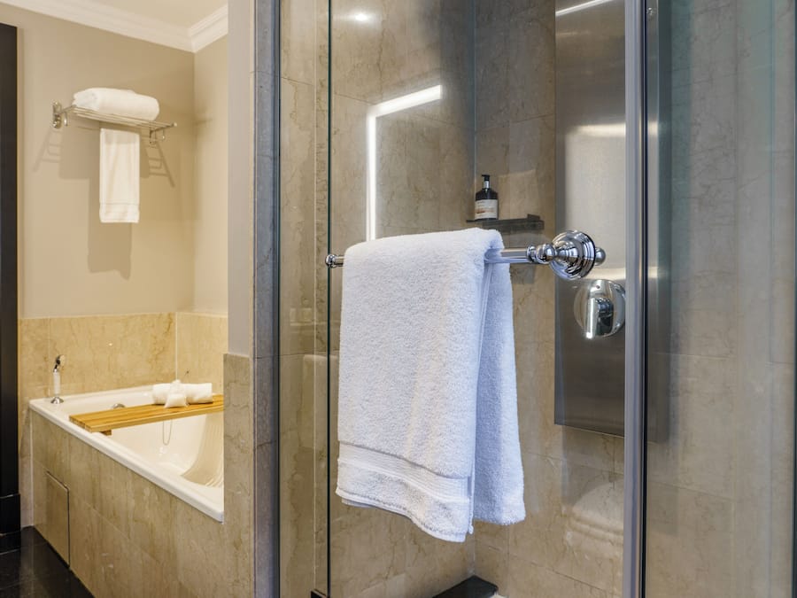 Ein modernes Badezimmer mit einer begehbaren Glasdusche, einer Badewanne und einem Handtuchhalter.