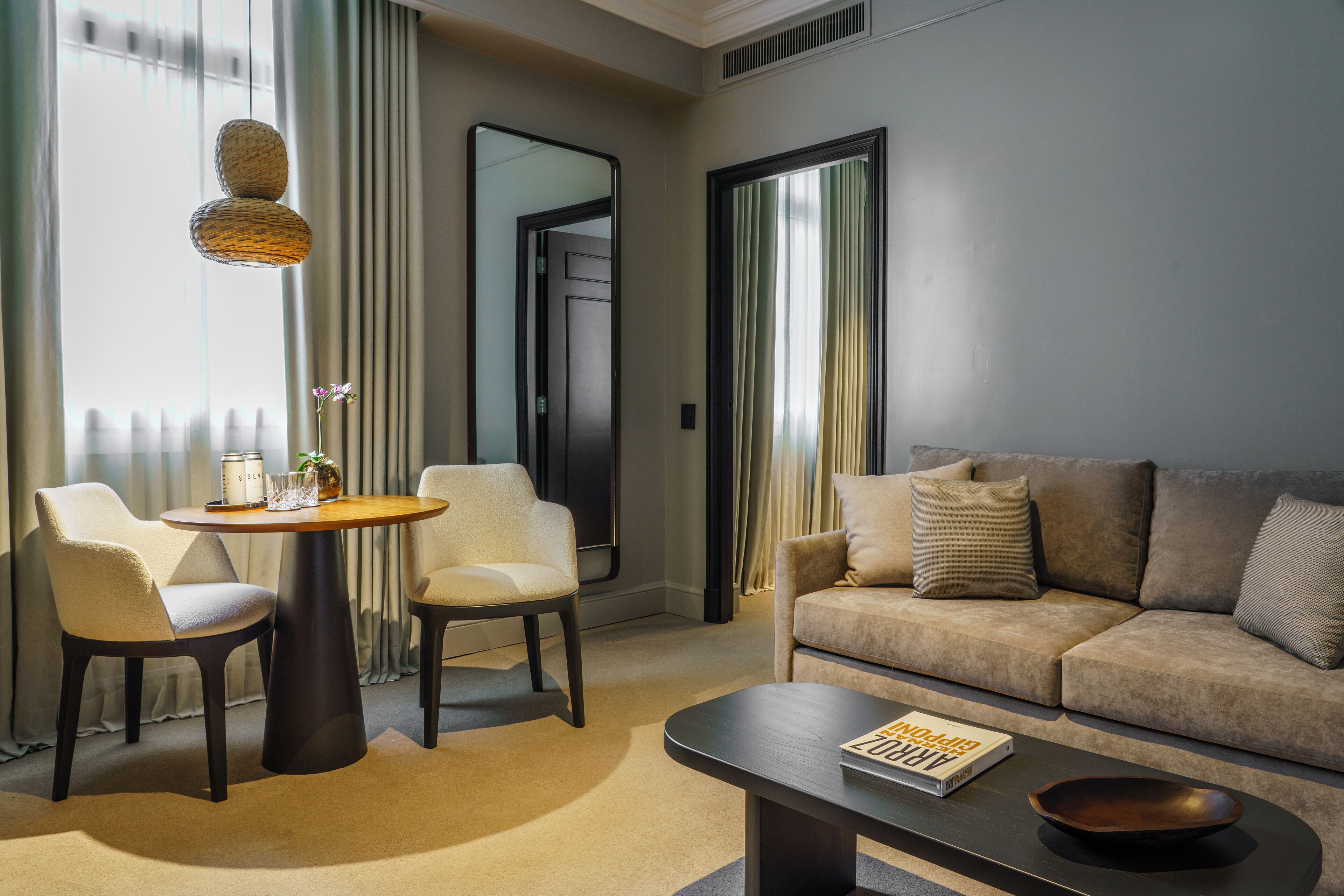 Et moderne hotelværelse med en sofa, to lænestole, et rundt bord og et sofabord.