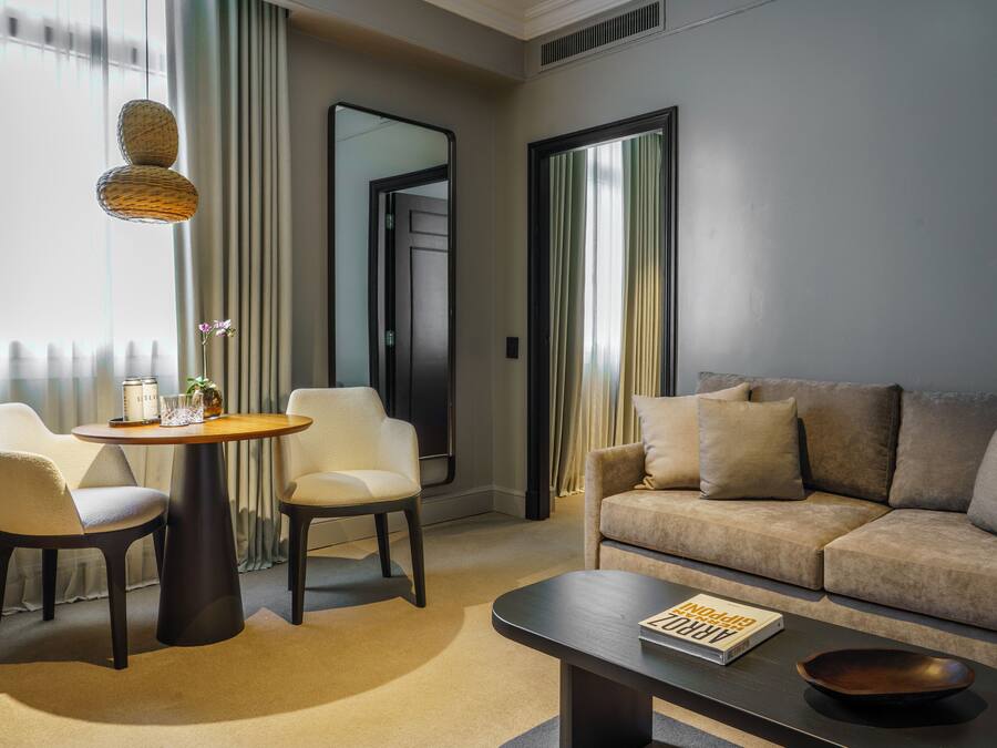 Et moderne hotelværelse med en sofa, to lænestole, et rundt bord og et sofabord.