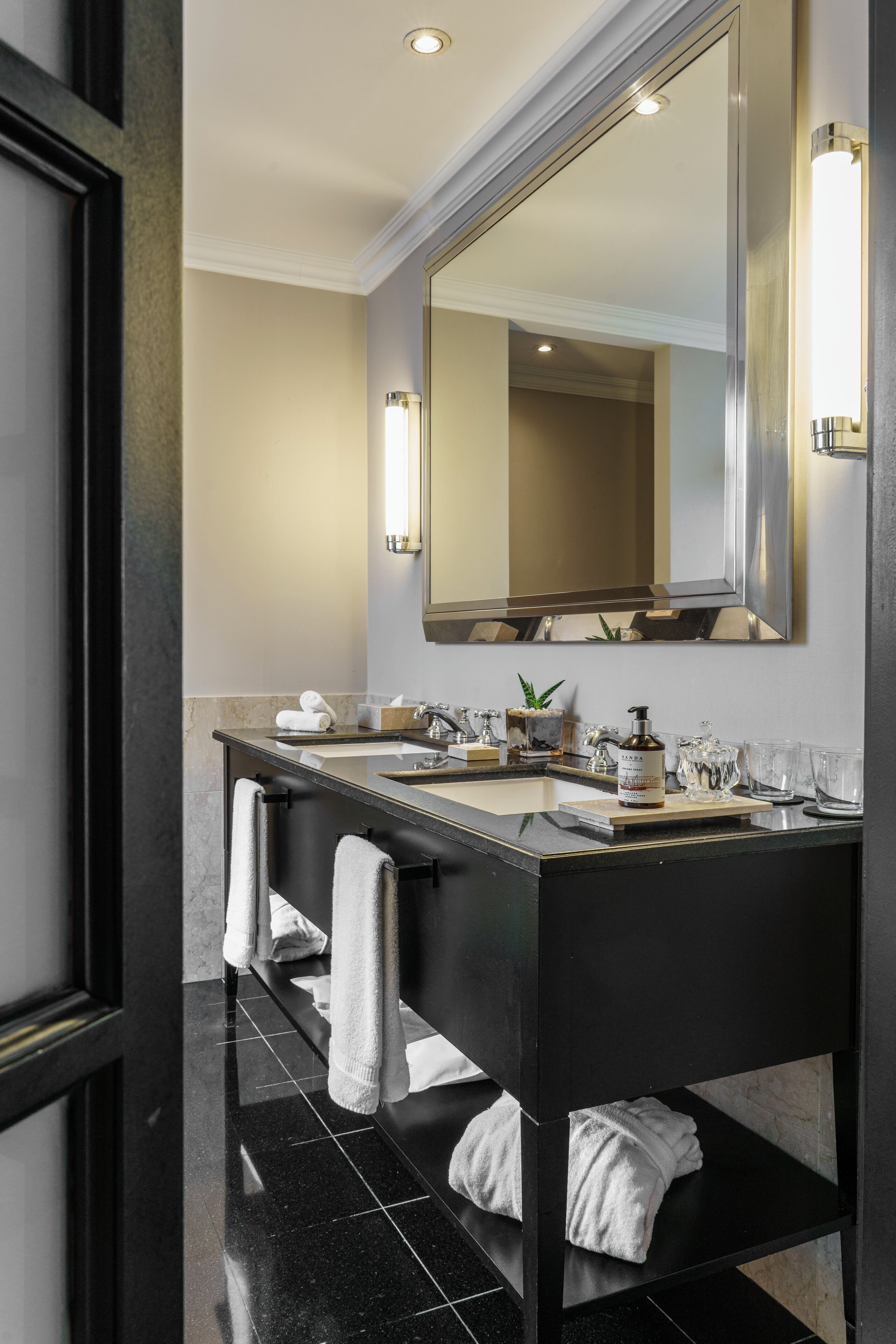 Un baño moderno con tocador doble, un espejo grande y un perchero para toallas.