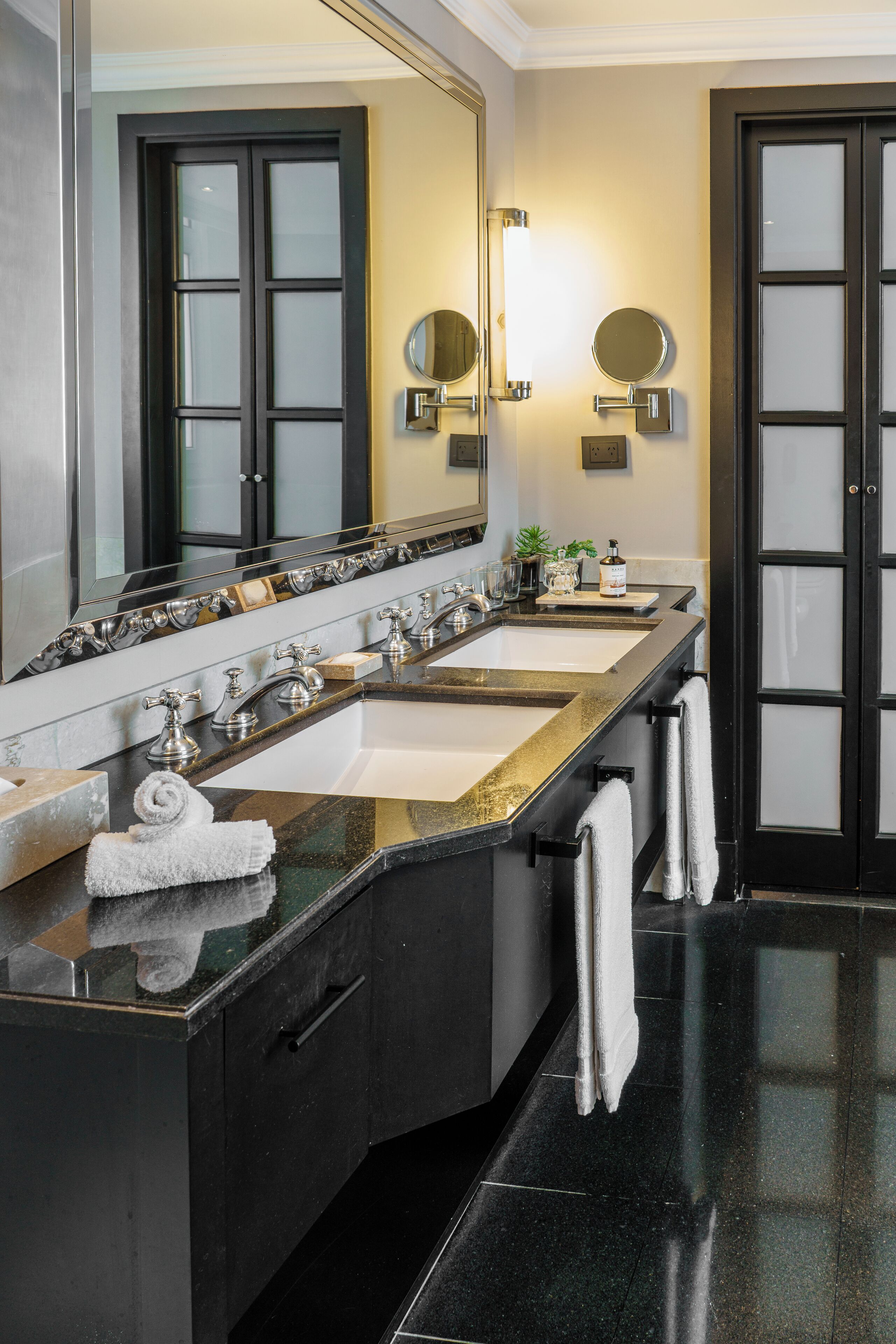 Un bagno moderno con un ampio lavabo, due bacinelle e uno specchio.