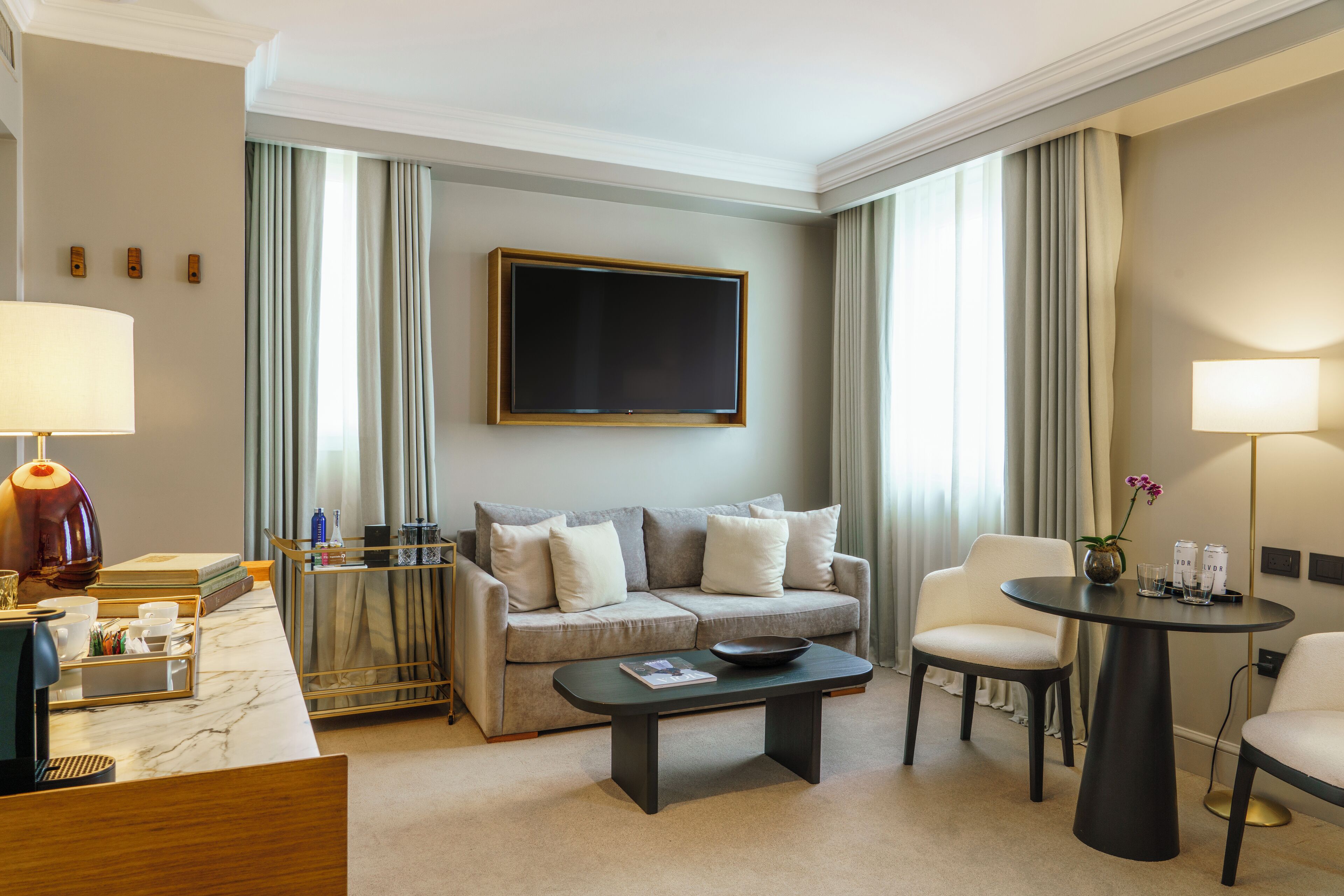 Une chambre d’hôtel moderne équipée d’un canapé, d’une table basse, d’une télévision et d’un coin repas.