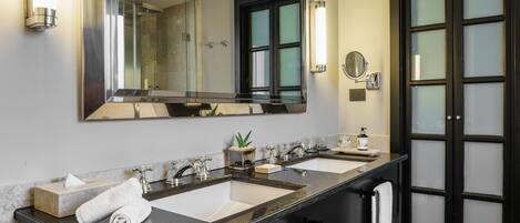 A modern bathroom with two sinks, a large mirror, and a black door with frosted glass panels.