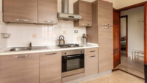A modern kitchen with wooden cabinets, a stainless steel sink, a gas stove, and an oven.