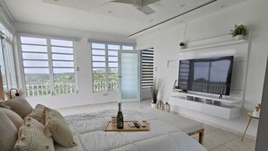 Ein geräumiges Schlafzimmer mit einem großen Bett, einem Deckenventilator, einem Fernseher und einem Balkon mit Aussicht.